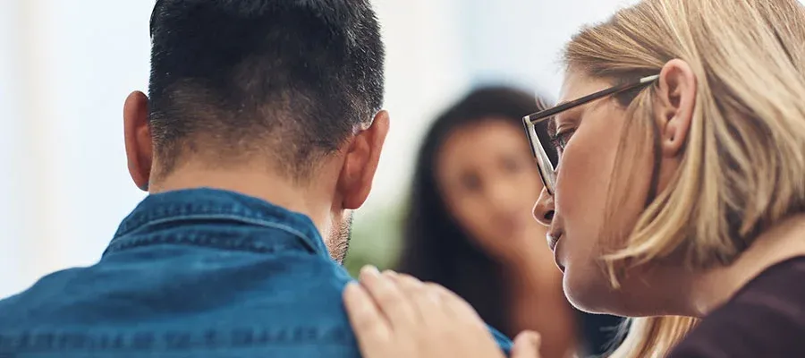 Women comforting man in blue shirt